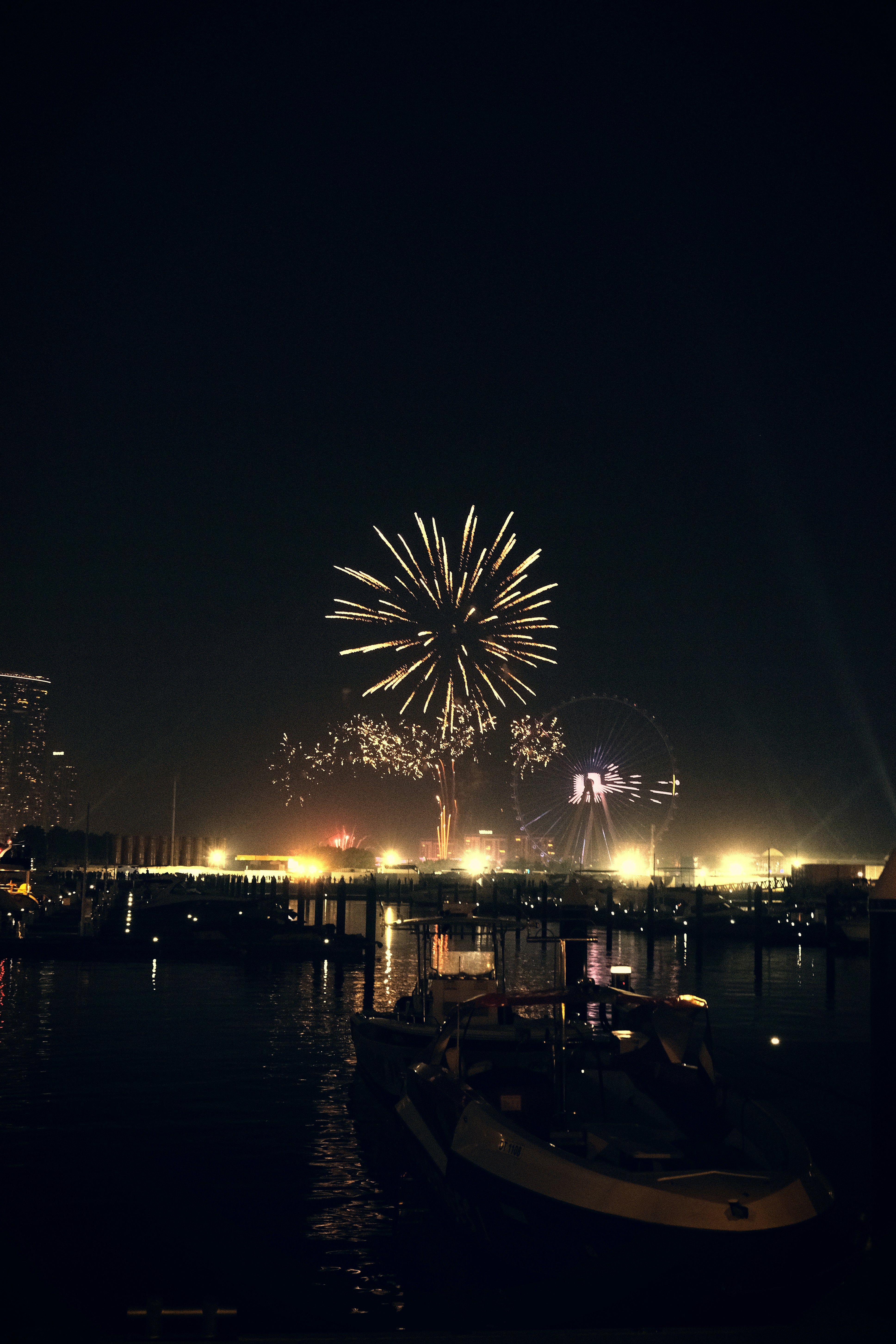 Fireworks are lit up in the night sky over a harbor