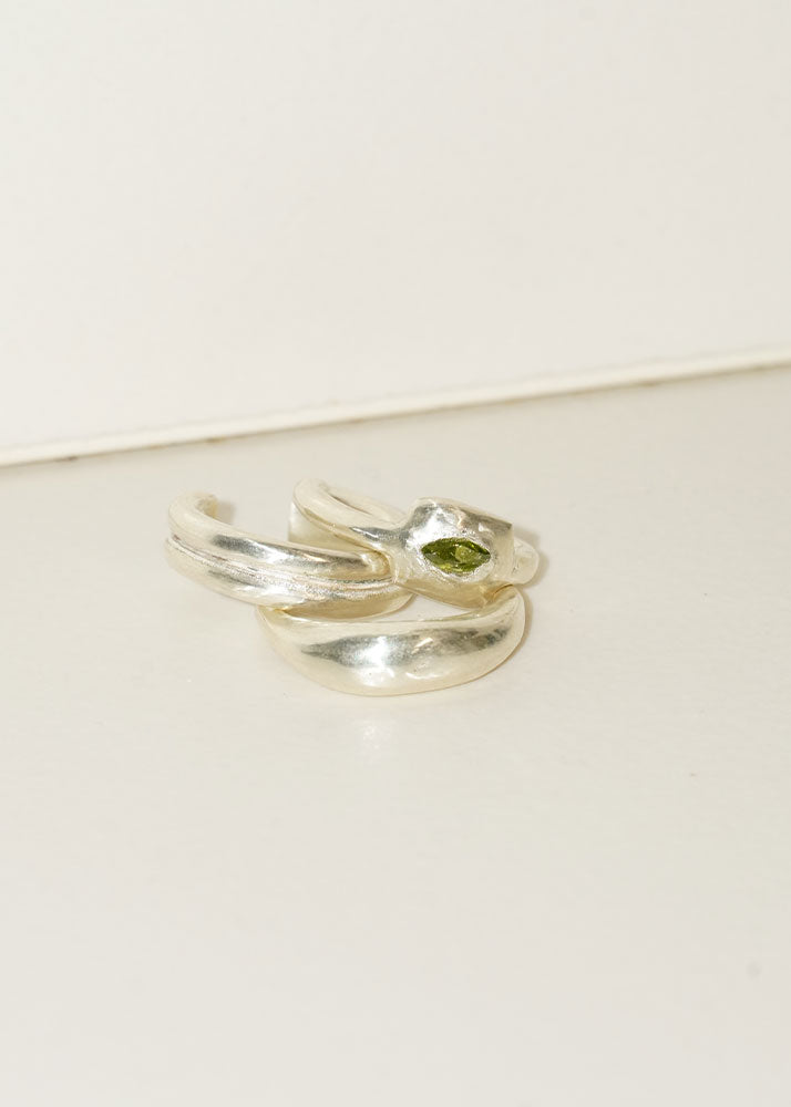 Two silver rings with green gemstones on a beige surface