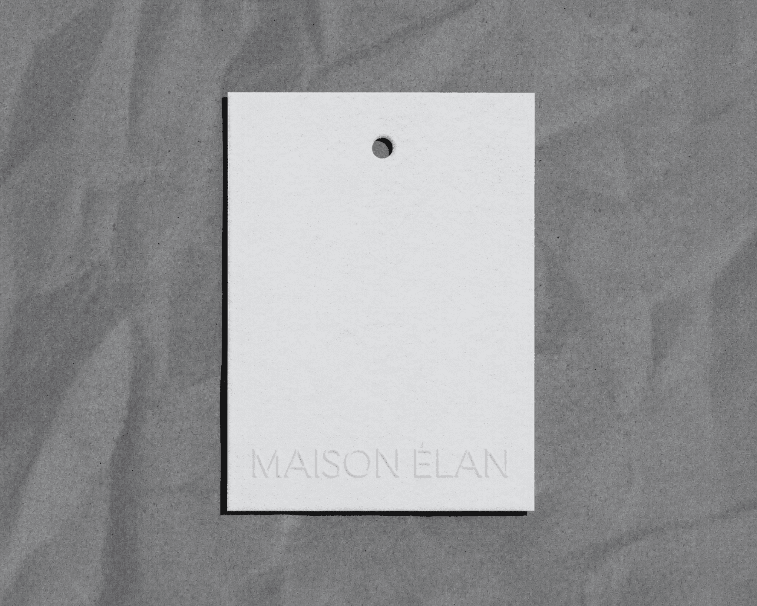 A Maison Élan tag. The tag is plain white with the brand logo embossed on the bottom.
