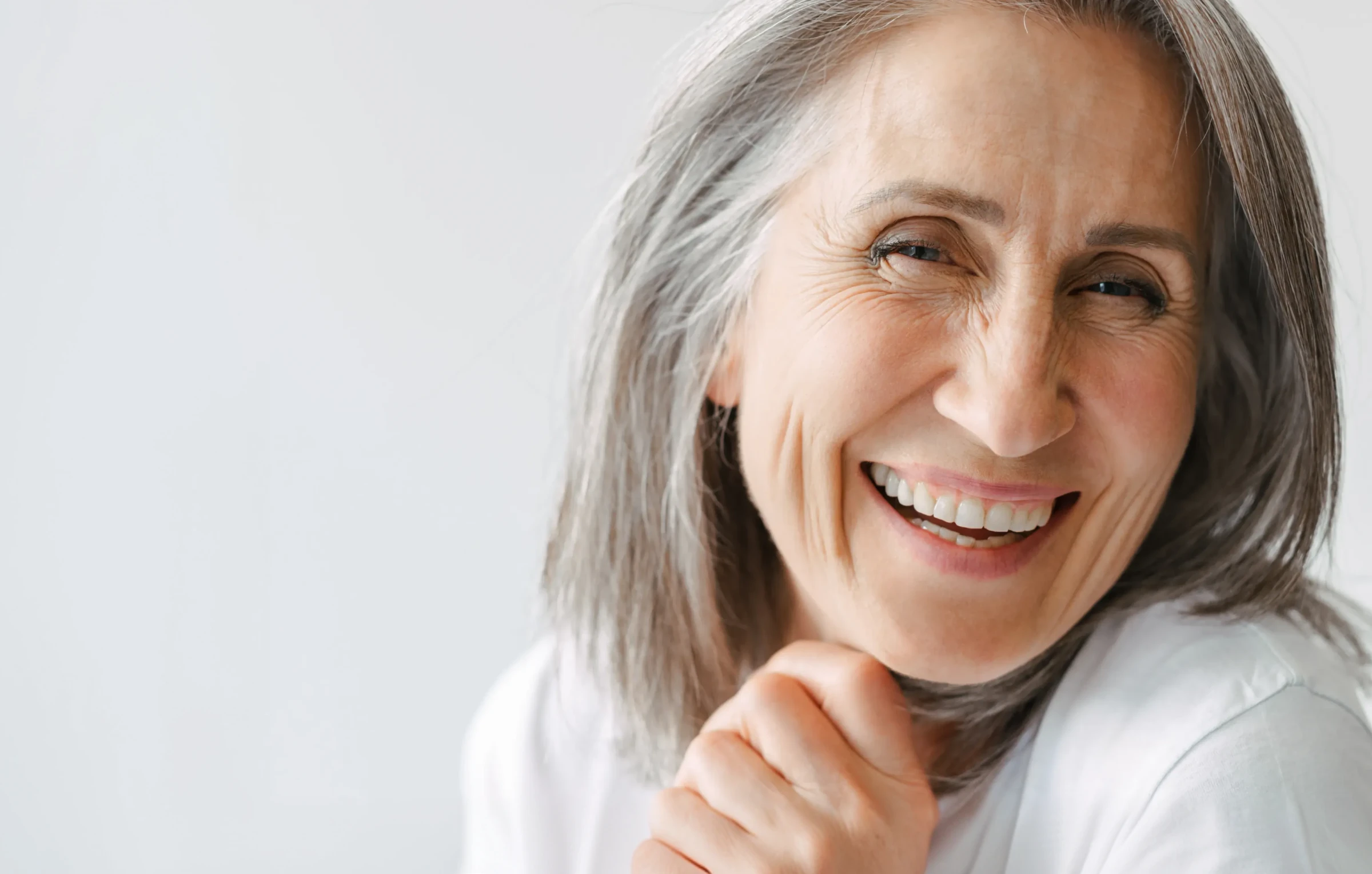 Kobieta z uśmiechem prezentująca efekty bondingu na swoich zębach.