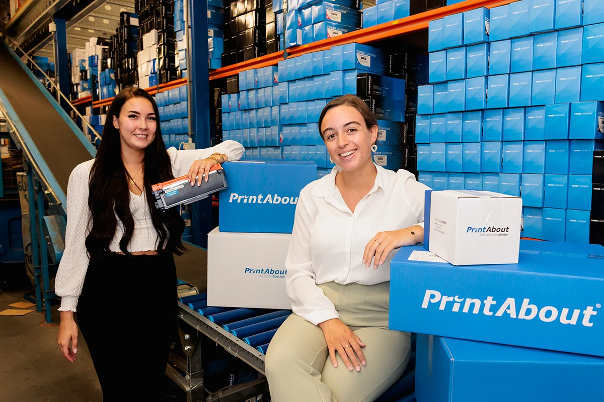 Twee medewerkers van PrintAbout met pakketten in het magazijn