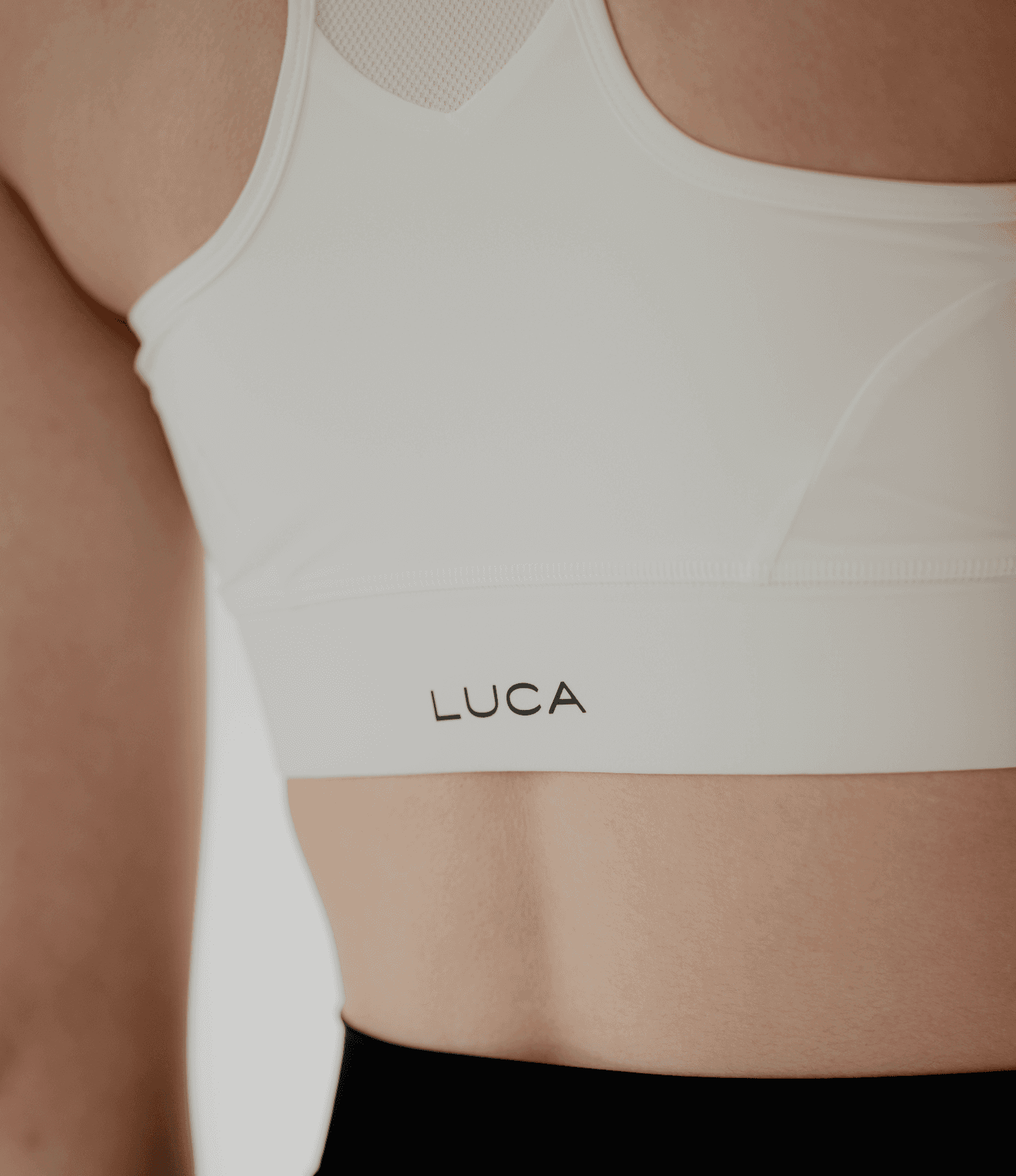 A-close-up-of-a-person-wearing-a-Sport-Bra-Off-White-with-the-brand-name-LUCA-printed-on-it