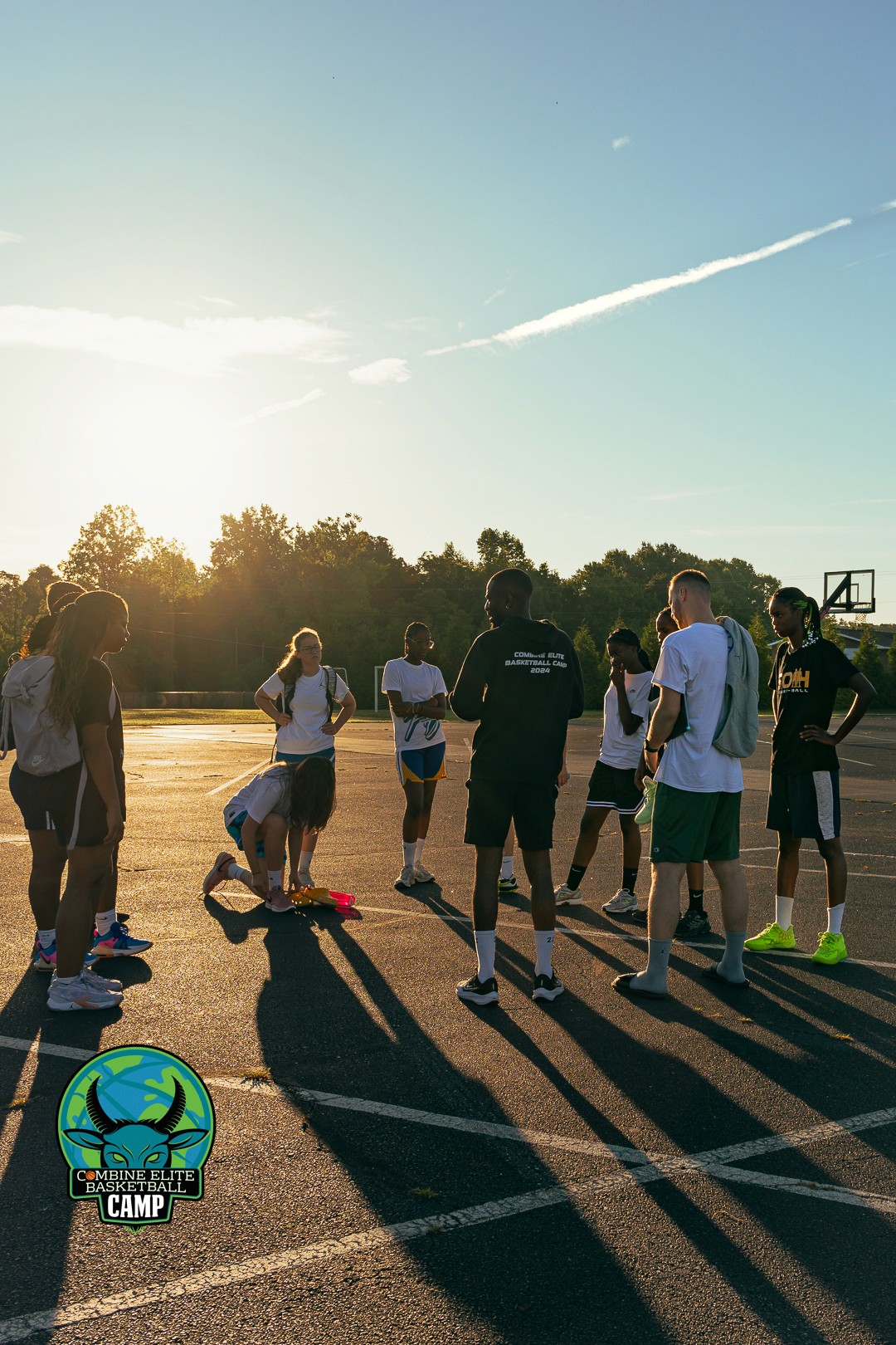 Groupe de jeunes participants d’un camp de basket réunis sur un terrain extérieur au lever de soleil.