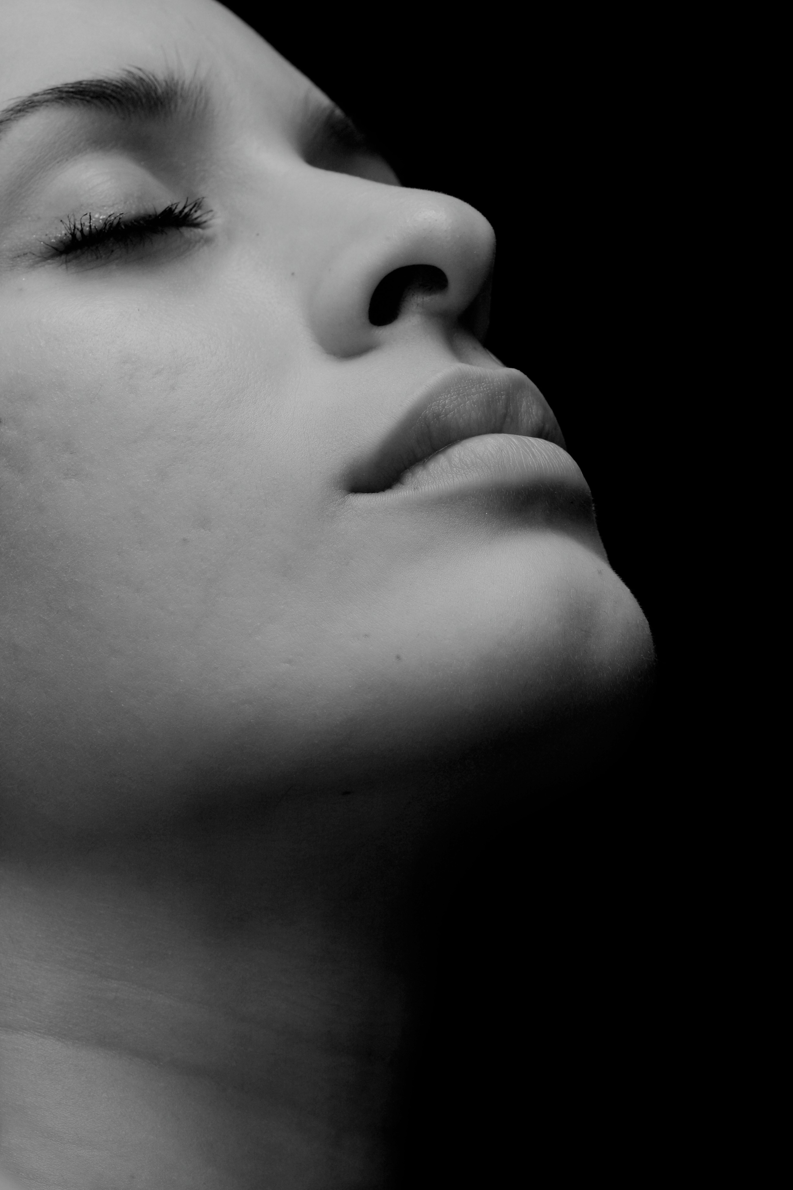 A young woman with wet hair, leaning back in a bath with her eyes closed. The sunlight reflects off the water, creating a serene and tranquil atmosphere.