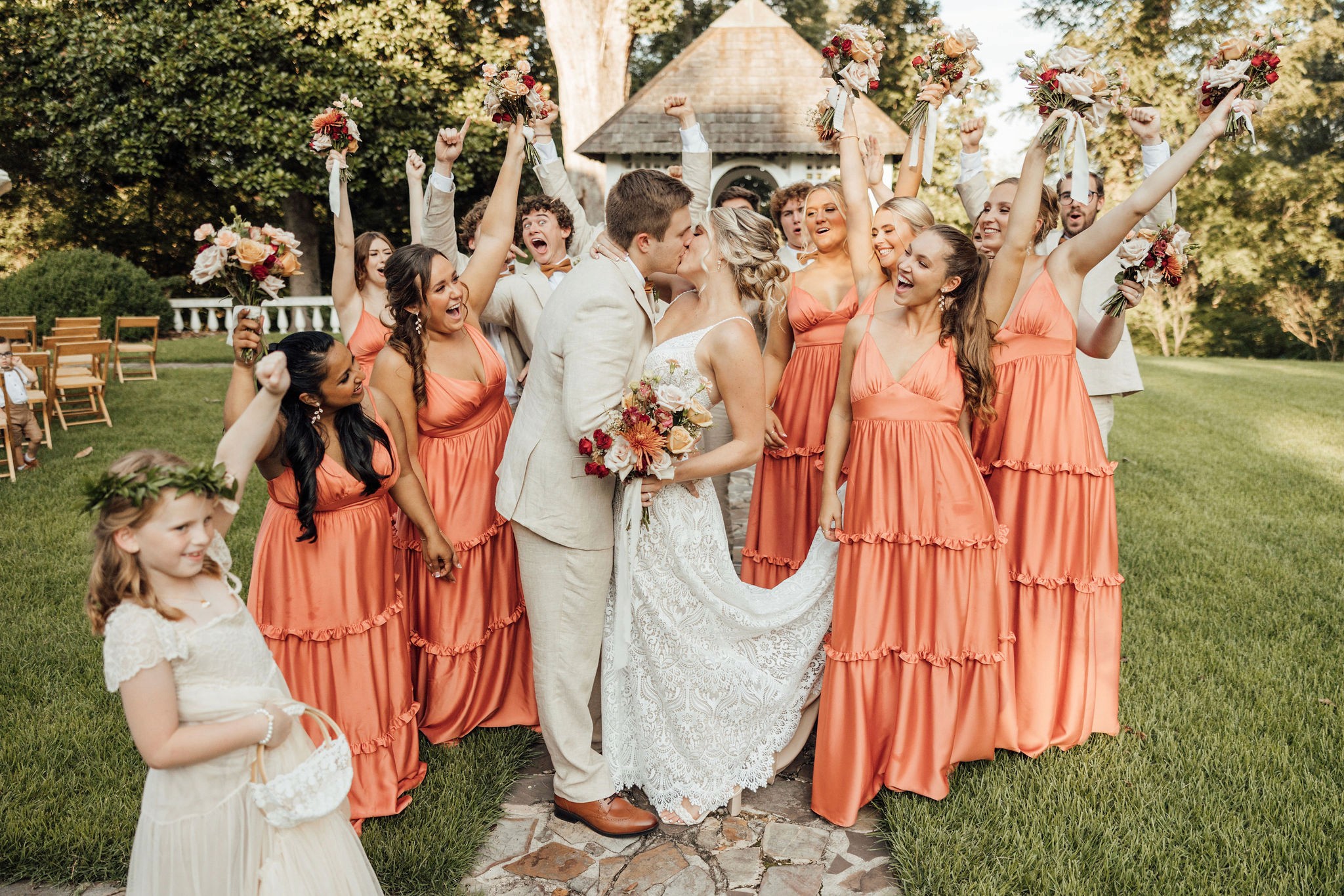 Wedding ceremony beneath a floral arch with attendants in coral dresses at Berry College.