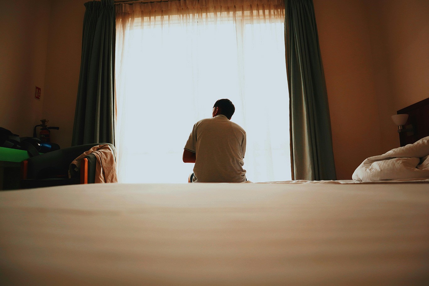 photo d'un homme sur le bord d'un lit, devant sa fenêtre, pointant les besoins de récupération plus que de repos