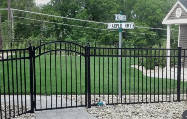 A black flat-top aluminum walk gate with a smooth top rail installed on a residential walkway.
