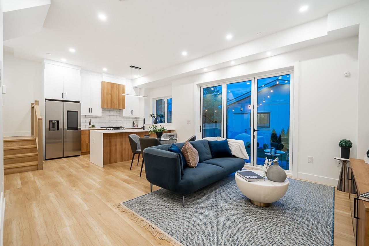 Modern living room featuring a blue sofa, large windows, and light wood flooring, creating a bright, airy atmosphere.