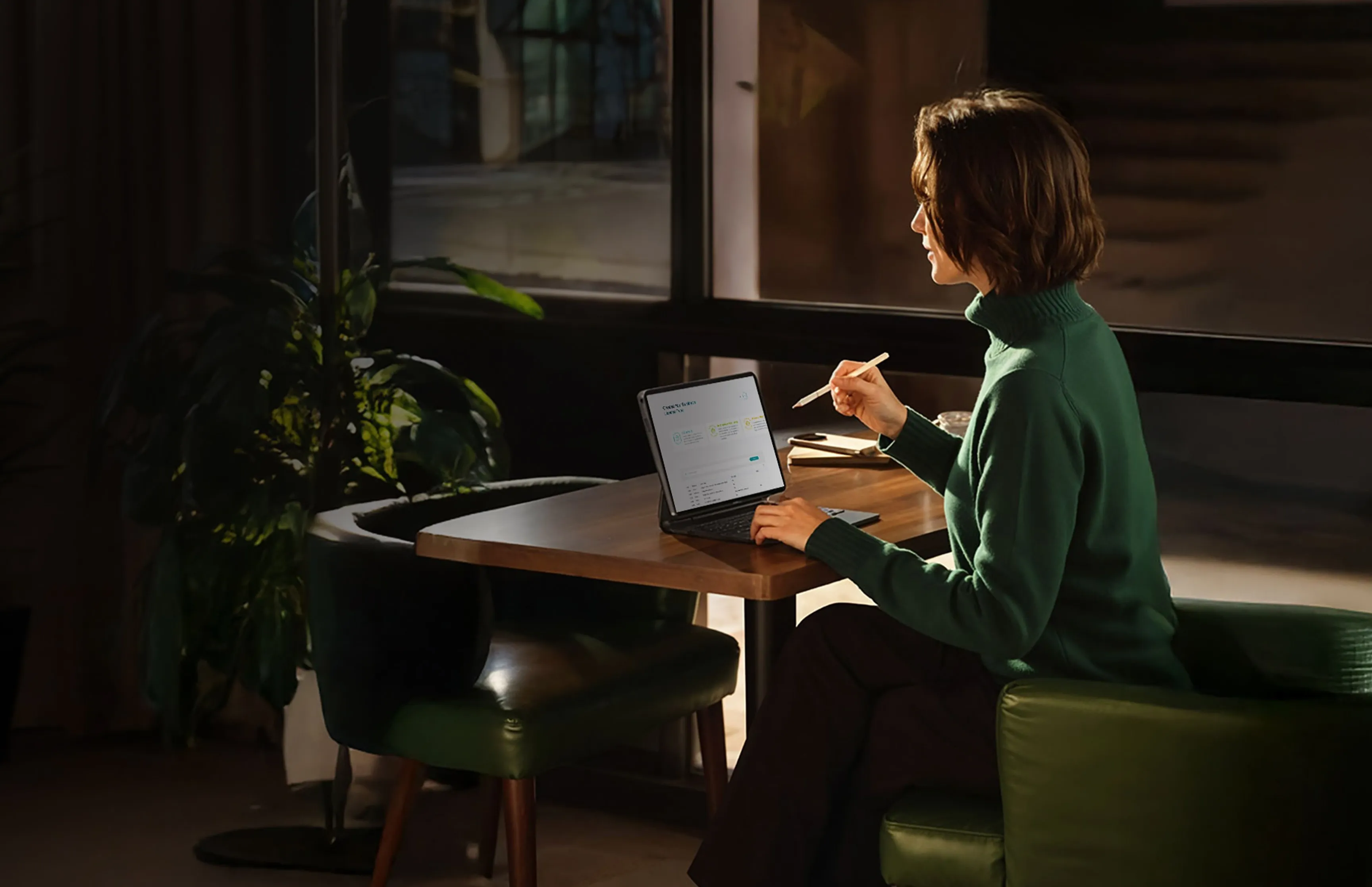 Dubai South Business Hub Free Zone -Woman working on a laptop at a table, using a stylus.