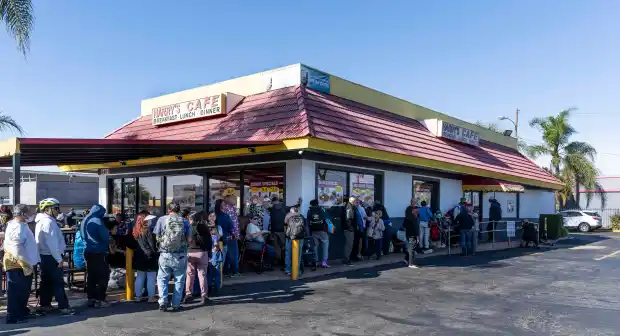 Crowded outside view of Harry's Cafe with customers lined up on the street on Thanksgiving