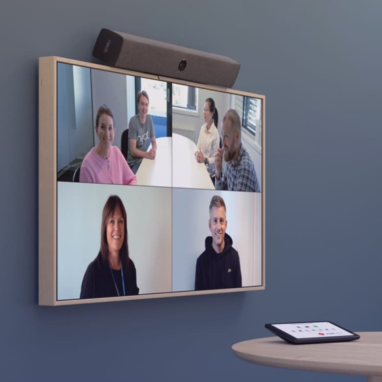 A group of people is visible on the monitor during a conference call.