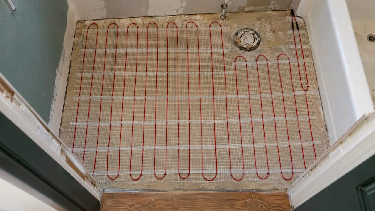 Electric heating mat laid over bathroom subfloor