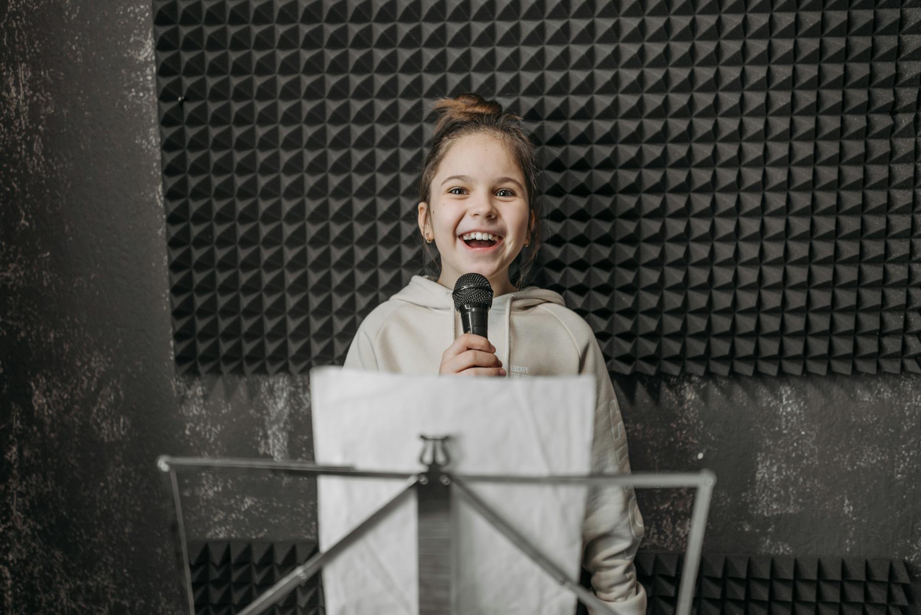 Diverse high school students singing together in a modern classroom equipped with microphones and recording gear.
