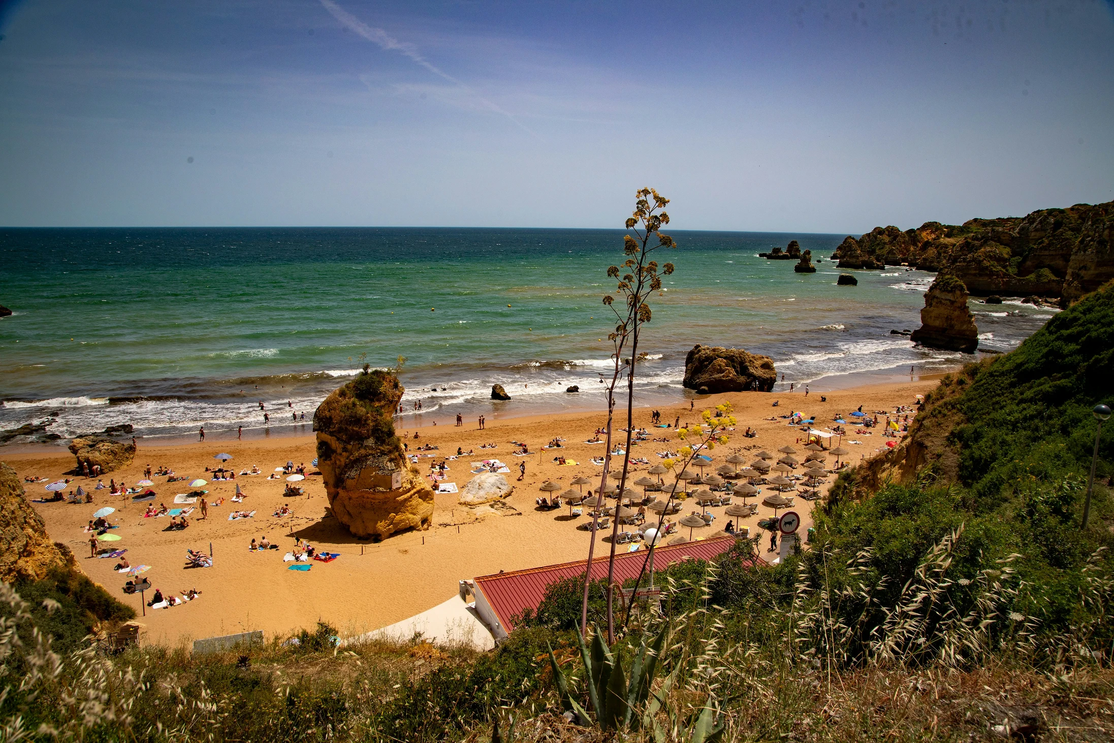 Praia de Faro beach with golden sand, turquoise water, and rocky coastline in the Algarve