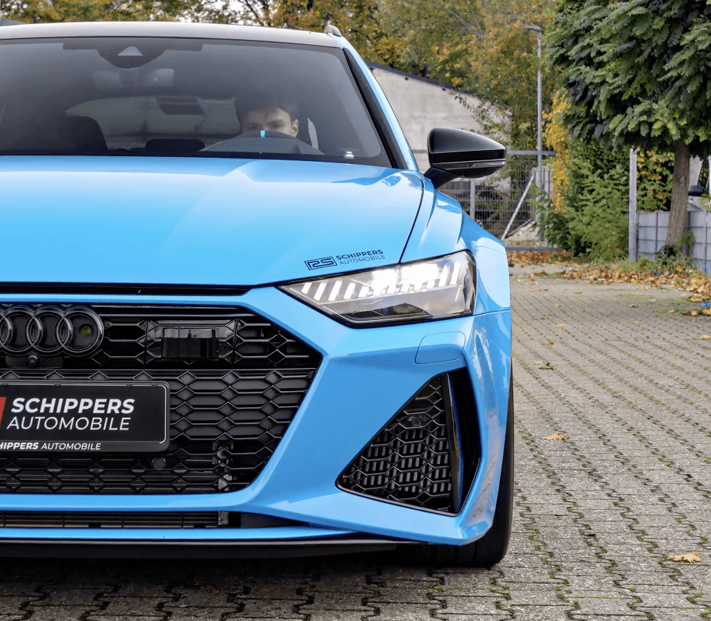 Modern white and glass villa with large windows, balconies, and palm trees in front under a bright blue sky.