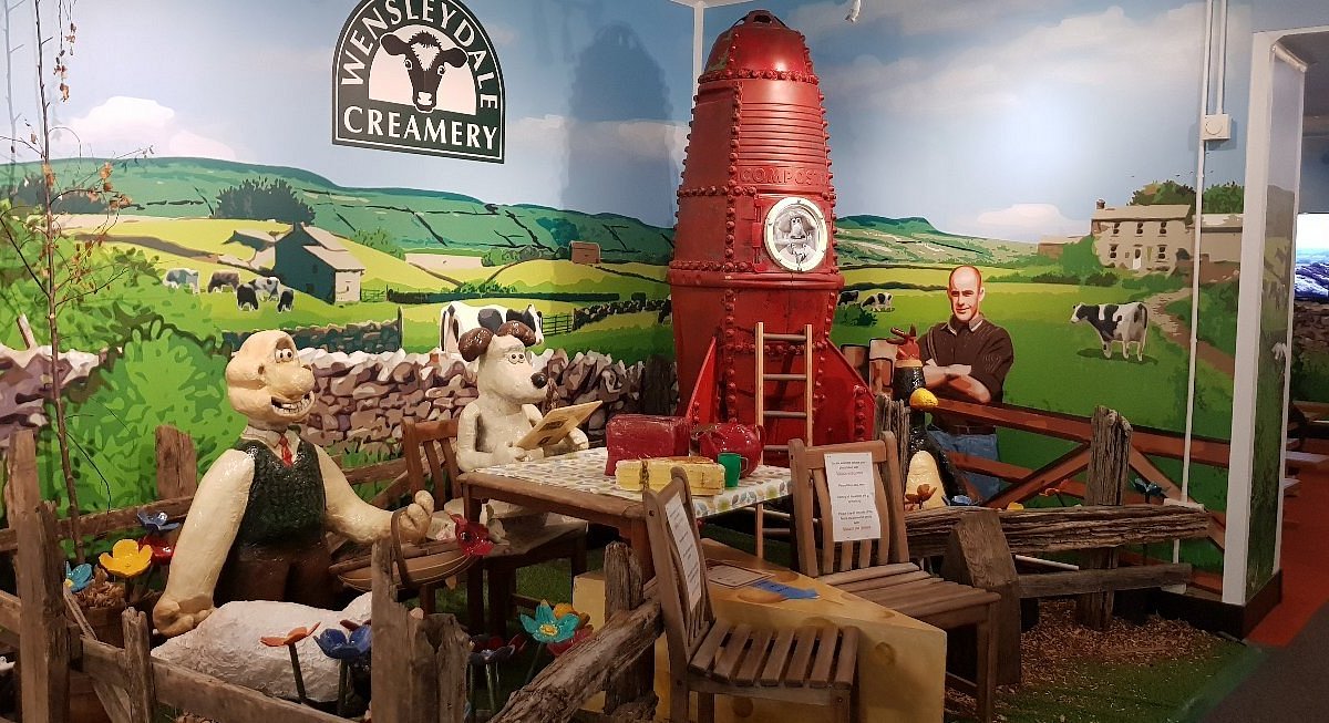 Wensleydale Creamery visitor attraction featuring colorful sheep characters, red rocket exhibit and Yorkshire Dales mural backdrop