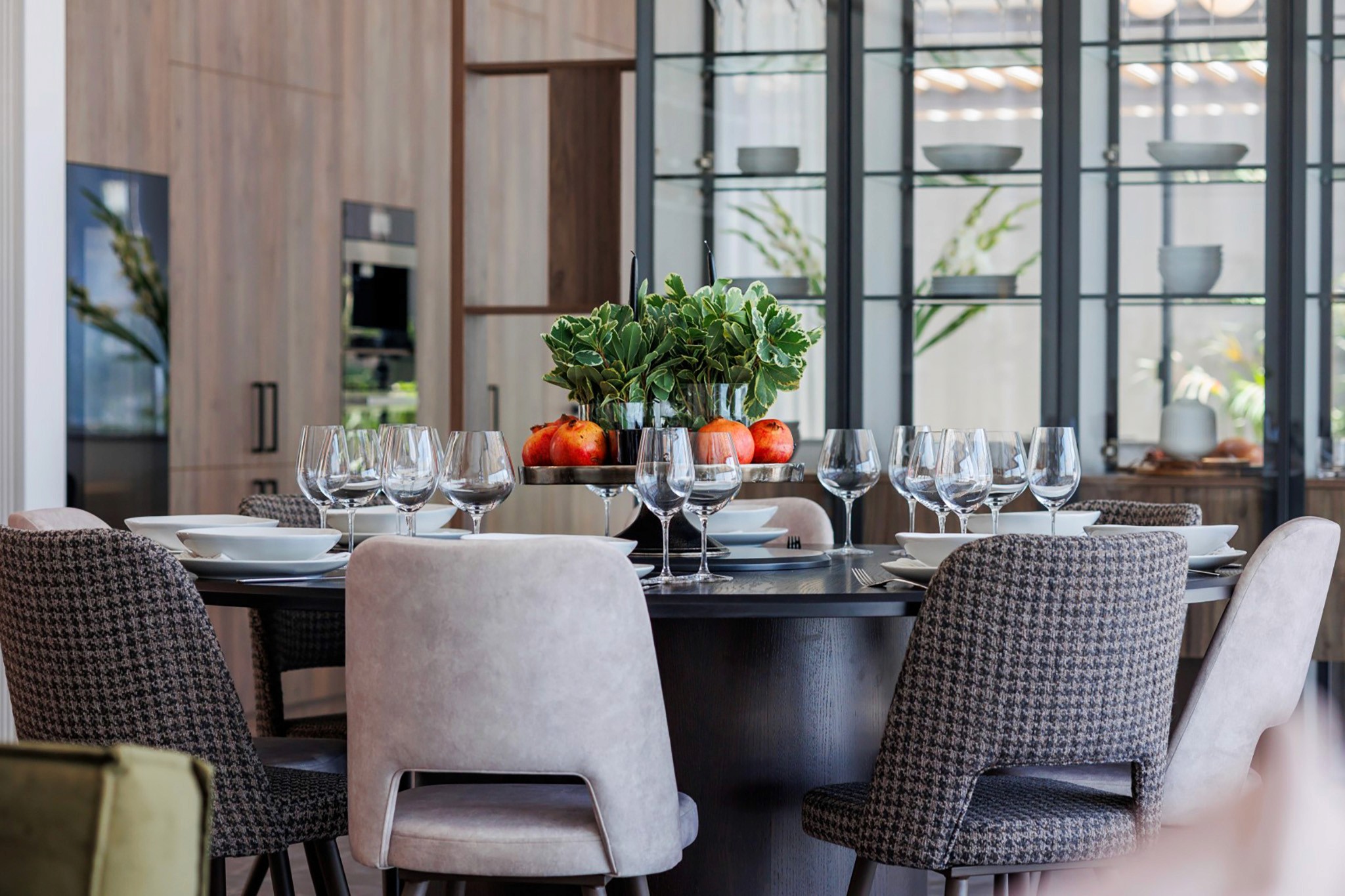 Villa Trio dining area with set table, upholstered chairs, and open-plan kitchen backdrop