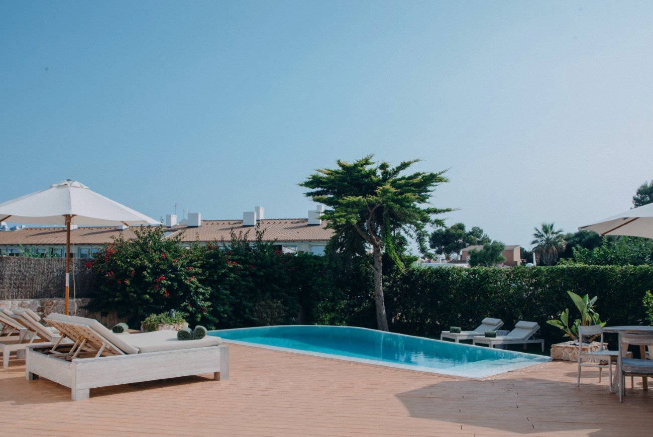 Luxuriöser Poolbereich mit Sonnenliegen und Sonnenschirmen unter blauem Himmel.