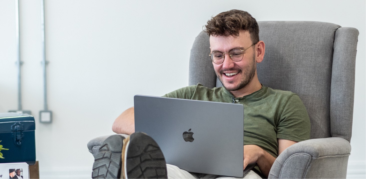 Person sitting on a couch using an open laptop.