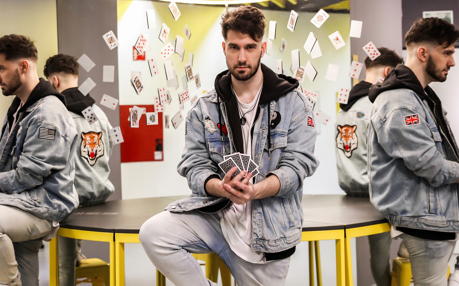 Mann som holder spillekort med refleksjoner og svevende kort på Illusjonsmuseet.