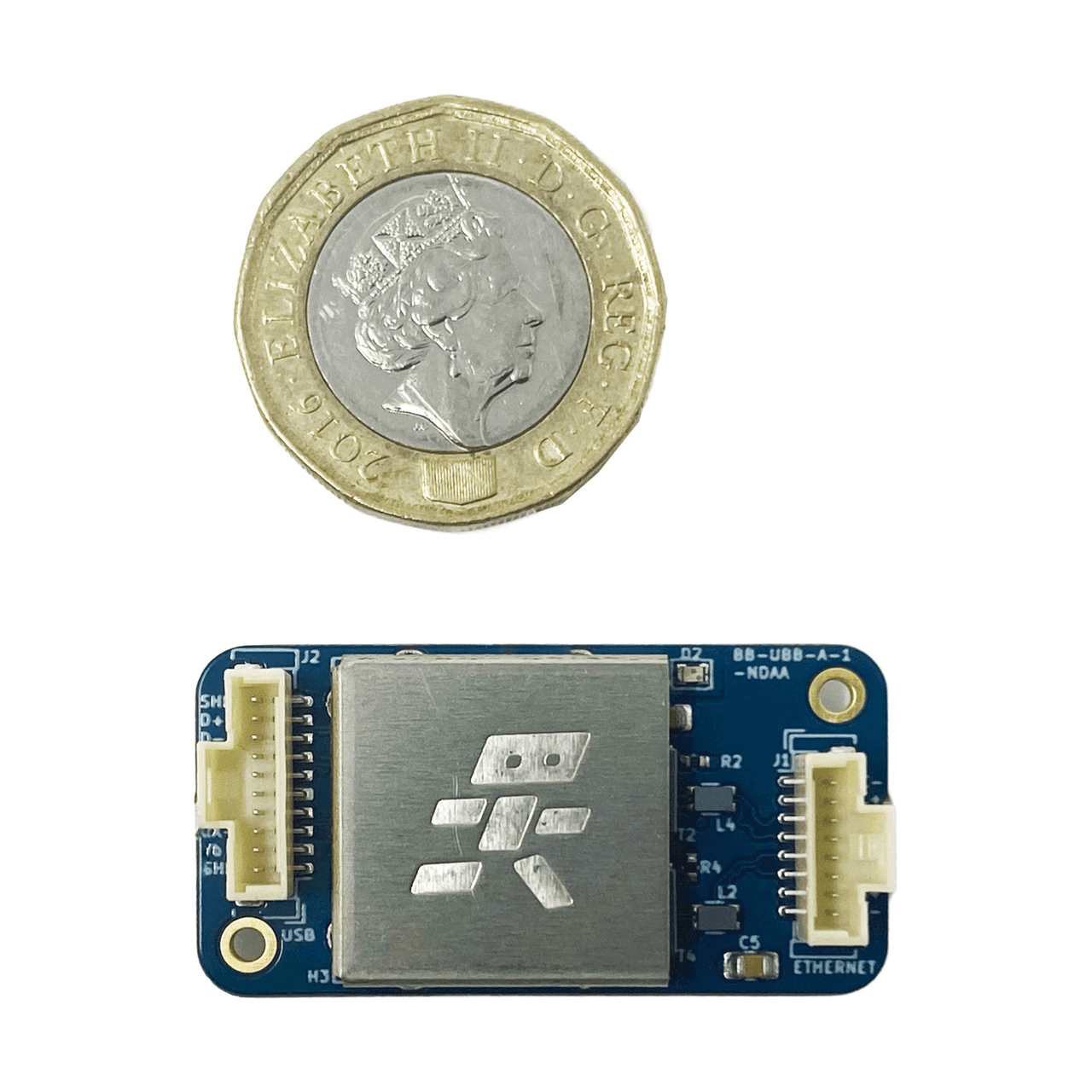 USBBlox board with its EMI shield next to a one-pound coin for scale