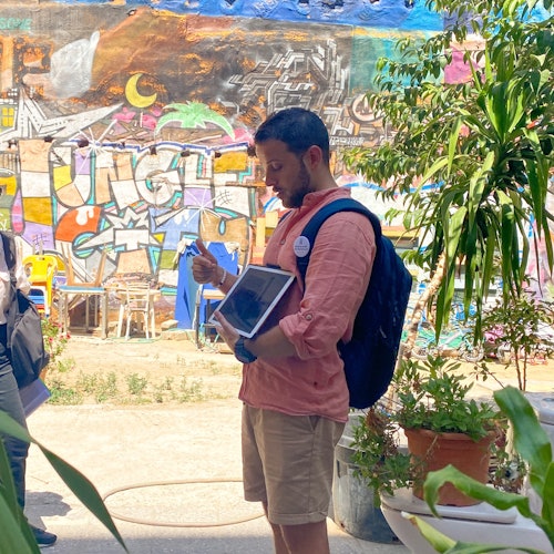 导游正在讲解这个邻里的情况，这里有装饰的墙面和许多绿植。