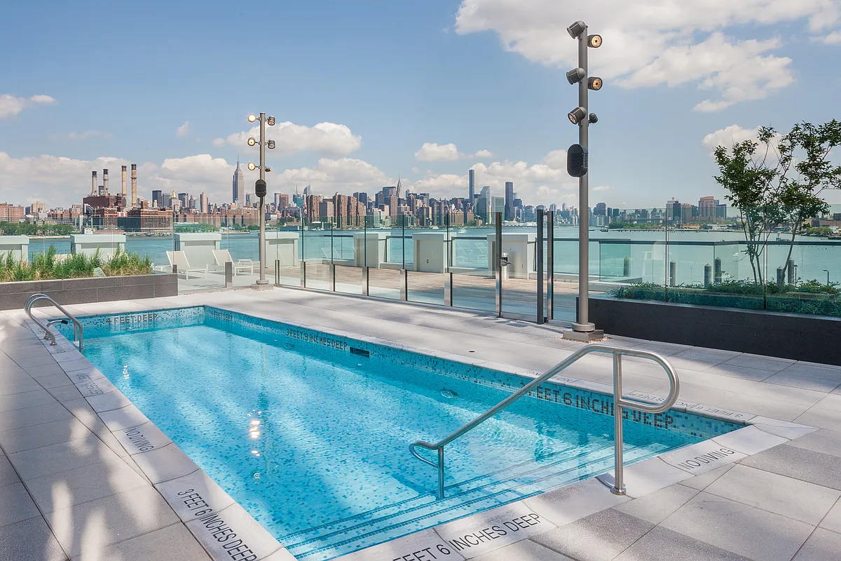 Elevated pool on a rooftop, overlooking a vibrant cityscape with skyscrapers in the distance.