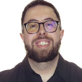 A woman with short curly hair wearing a black t-shirt looks into the camera.