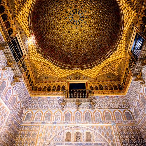 Un techo abovedado ricamente decorado con intrincados patrones geométricos, ventanas arqueadas y diseños de paredes elaborados en un edificio histórico.