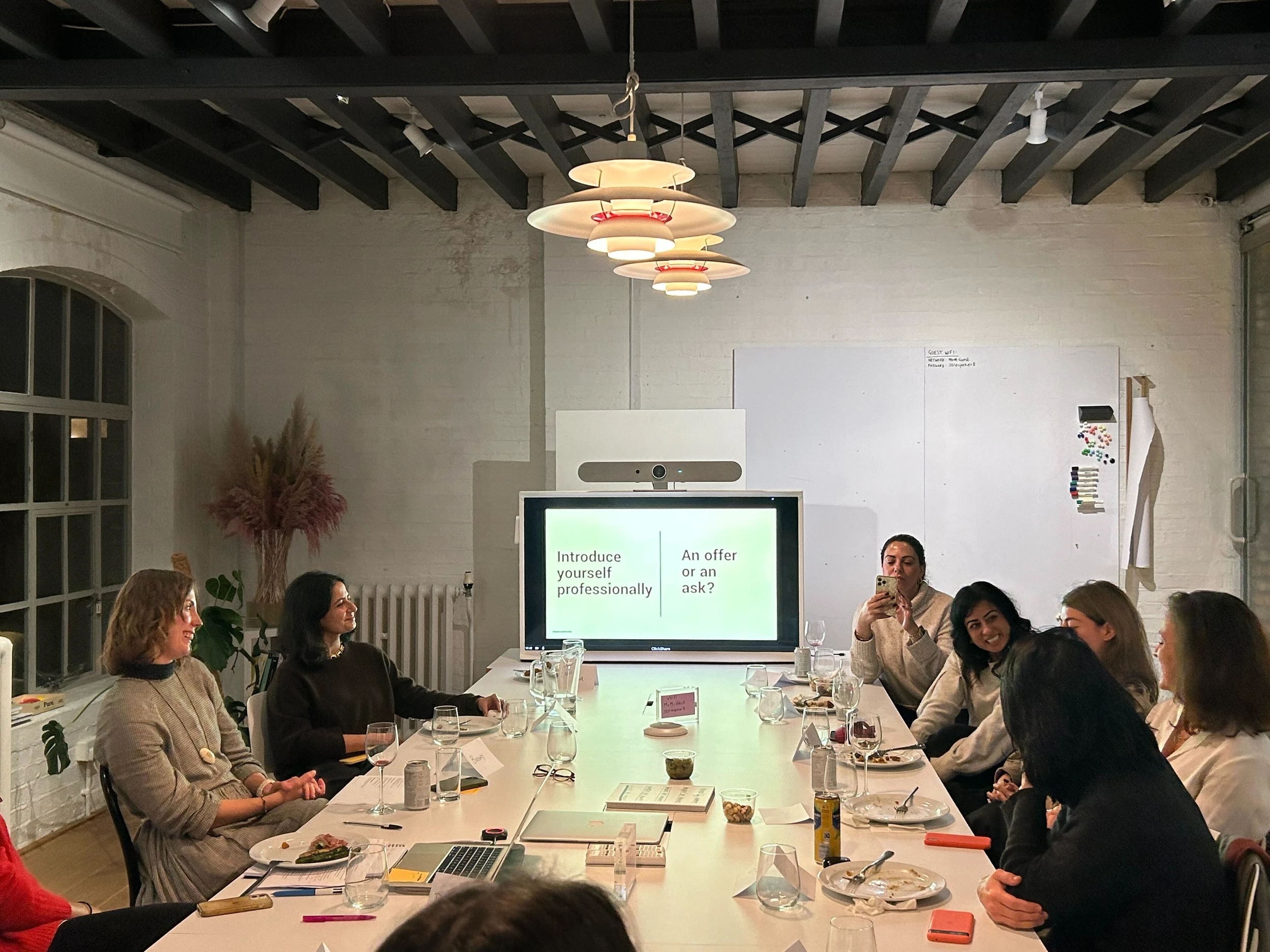 A group of women sitting at a long table with a slide displaying "Introduce yourself professionally"