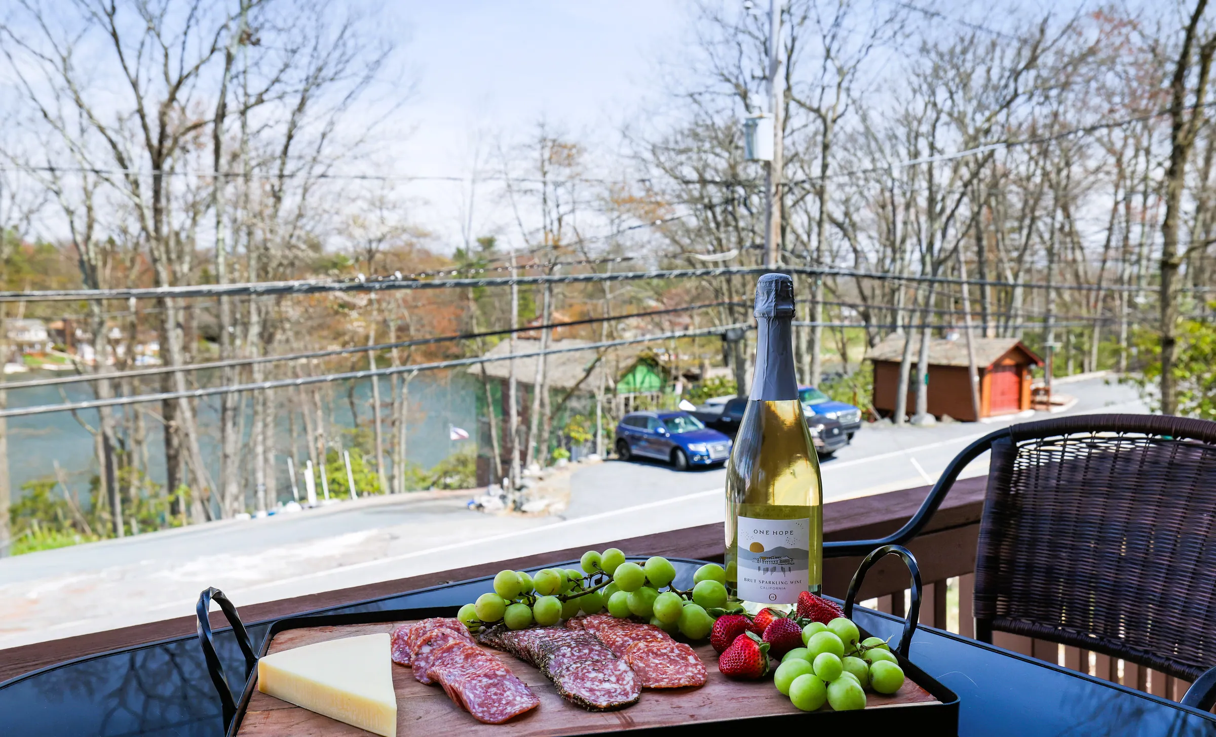Charcuterie board and sparkling wine on the balcony table with lake glimpses at Repeat Retreat, Lake Harmony