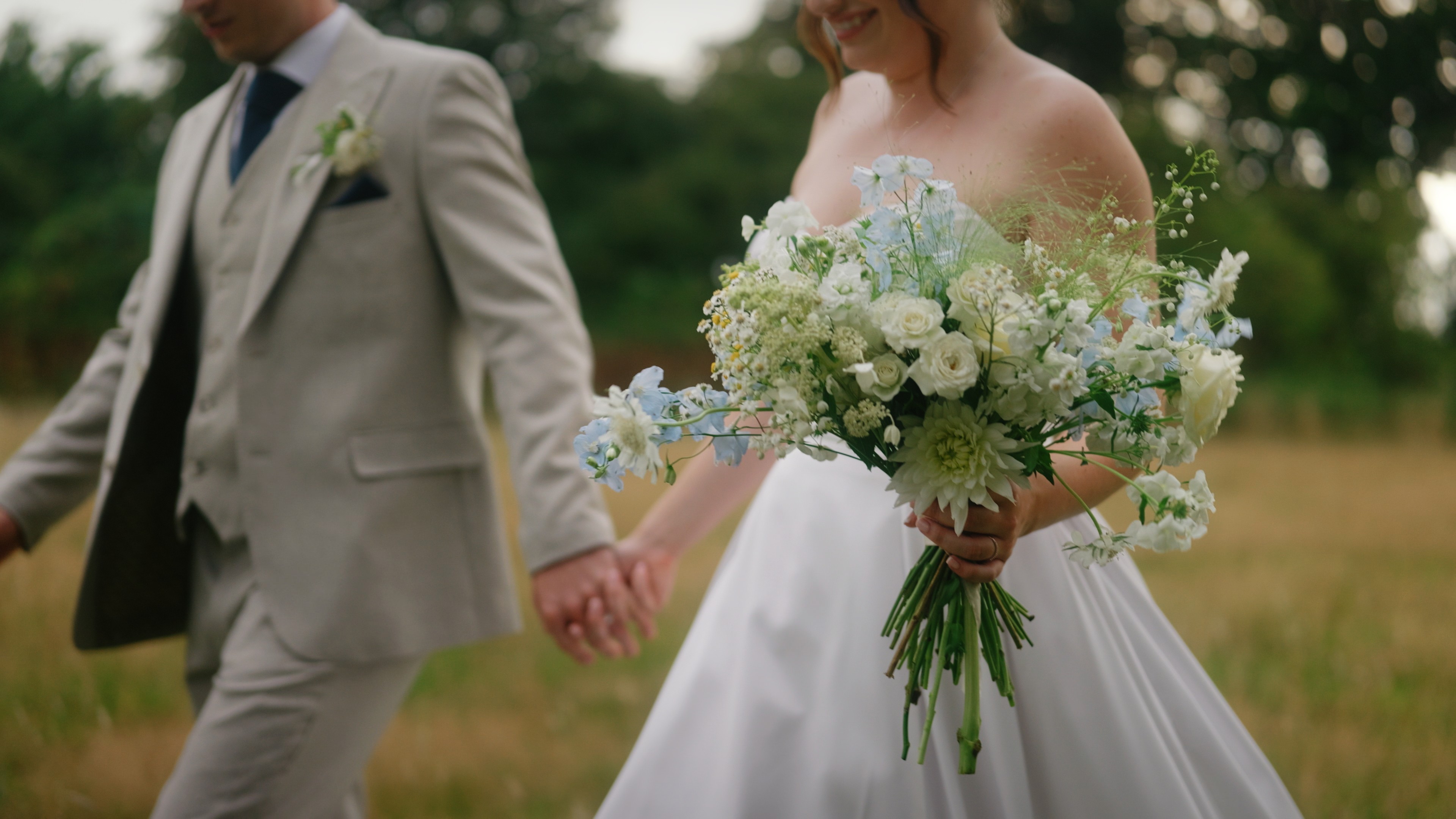 Bride and groom holding hands during relaxed wedding portraits at Aswarby Rectory in Lincolnshire, with the bride carrying her bouquet