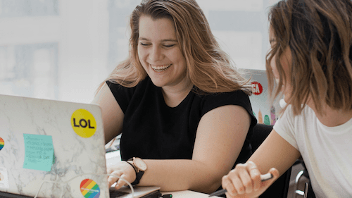 Two women smiling working side-by-side.