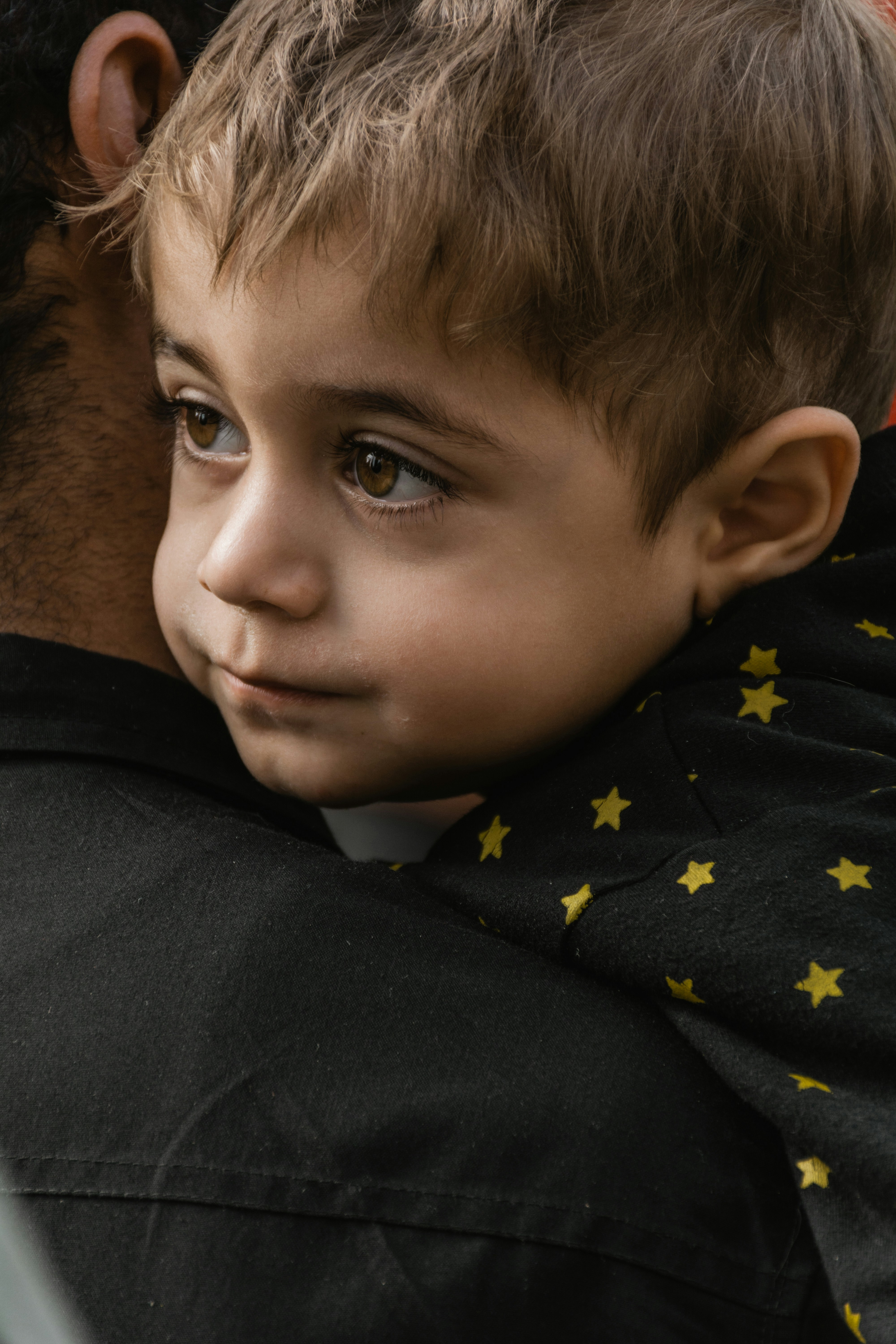 a young boy is holding his father's shoulder