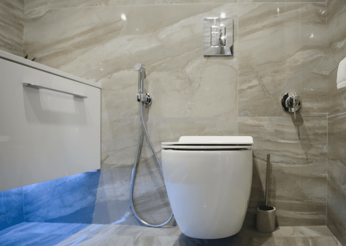 Badezimmerdetail mit wandhängendem WC, Spülkasten und moderner Beleuchtung.