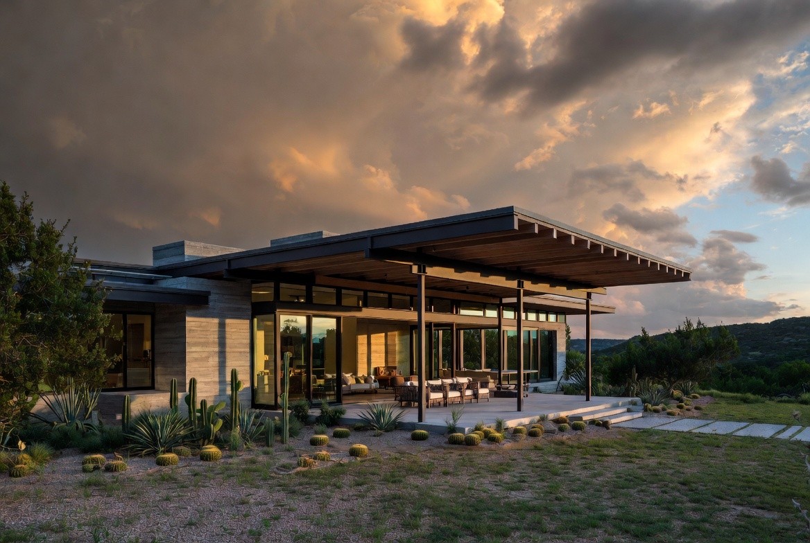 Contemporary Hill Country home exterior with covered terrace and desert landscaping at sunset