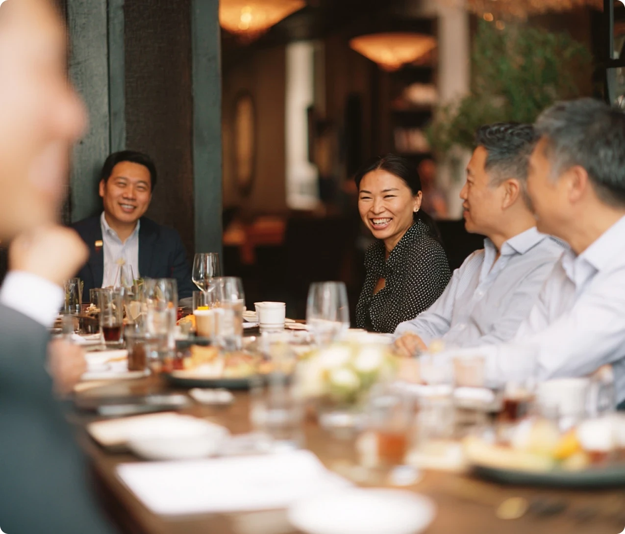 Young man in a green hoodie holding a yellow phone while seated at a table with a tablet.