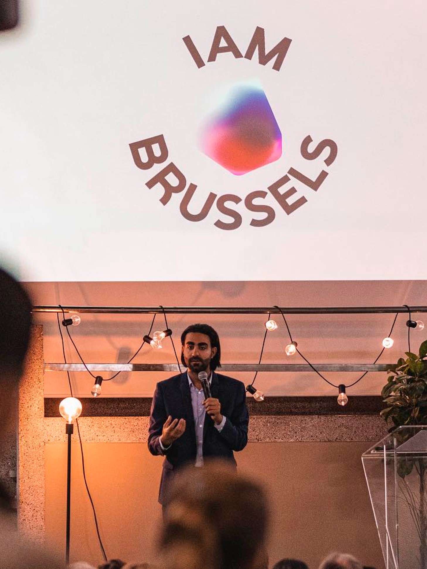 Modern home office setup with a monitor, ergonomic chair, keyboard, and indoor plants near a window with blinds.