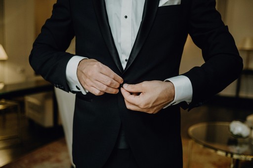 a man in a tuxedo tying his tie illustrating concierge