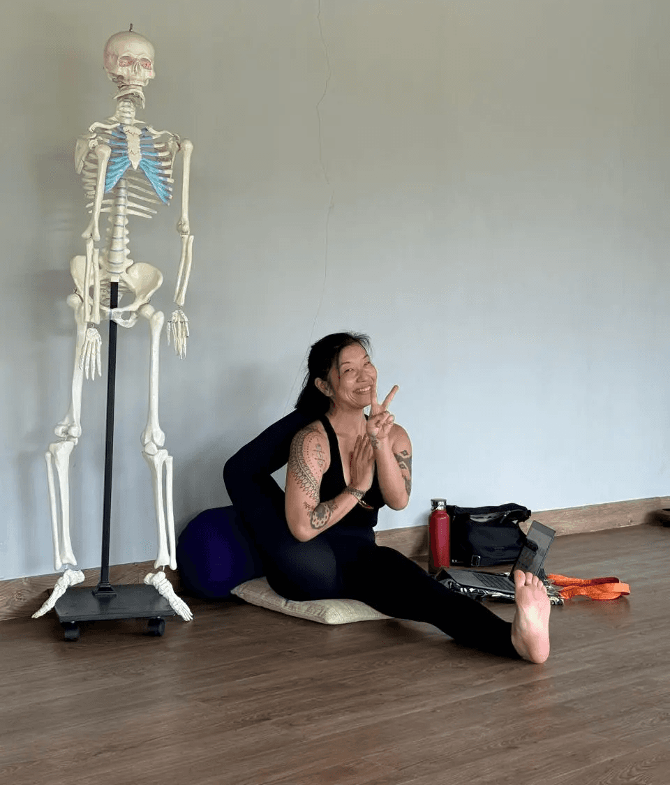 Vivienne Zeng riding a yellow scooter in Bali, enjoying the tropical lifestyle during yoga teacher training downtime.