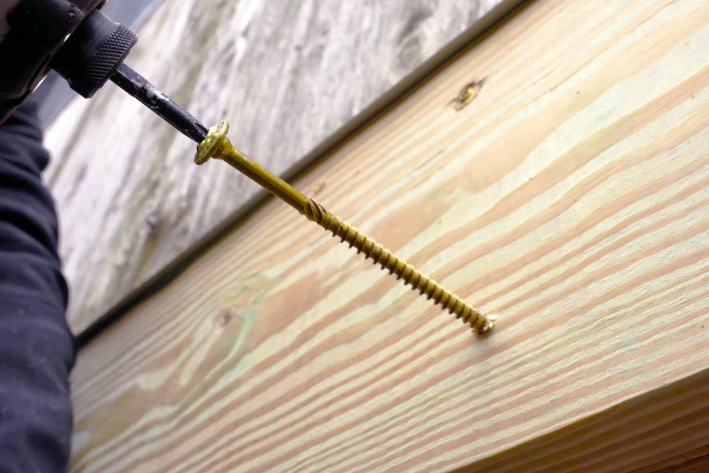 Bright coastal living room with soft natural light, stone flooring, neutral furnishings, and floor-to-ceiling glass opening to an outdoor patio.