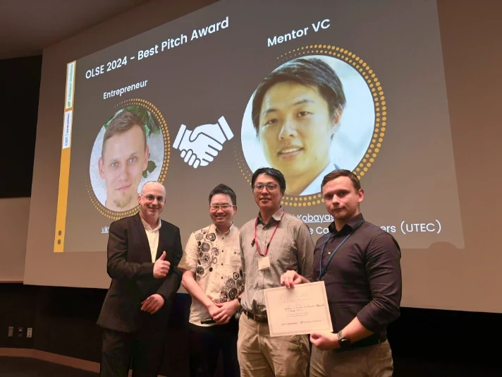 Award ceremony with five individuals posing in front of a screen displaying “Best Pitch Award” and “Mentor VC.”