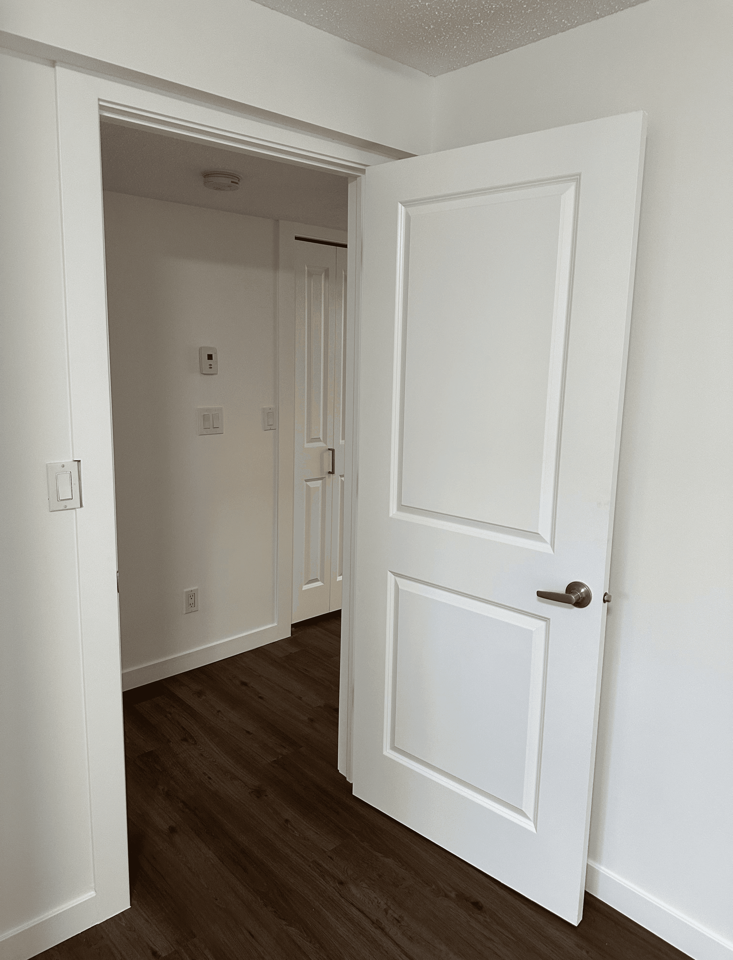 A talent recruiter with a soft smile working on her laptop in the office. The angle is on her face so we can't see what's is on the screen. She is wearing a blazer 