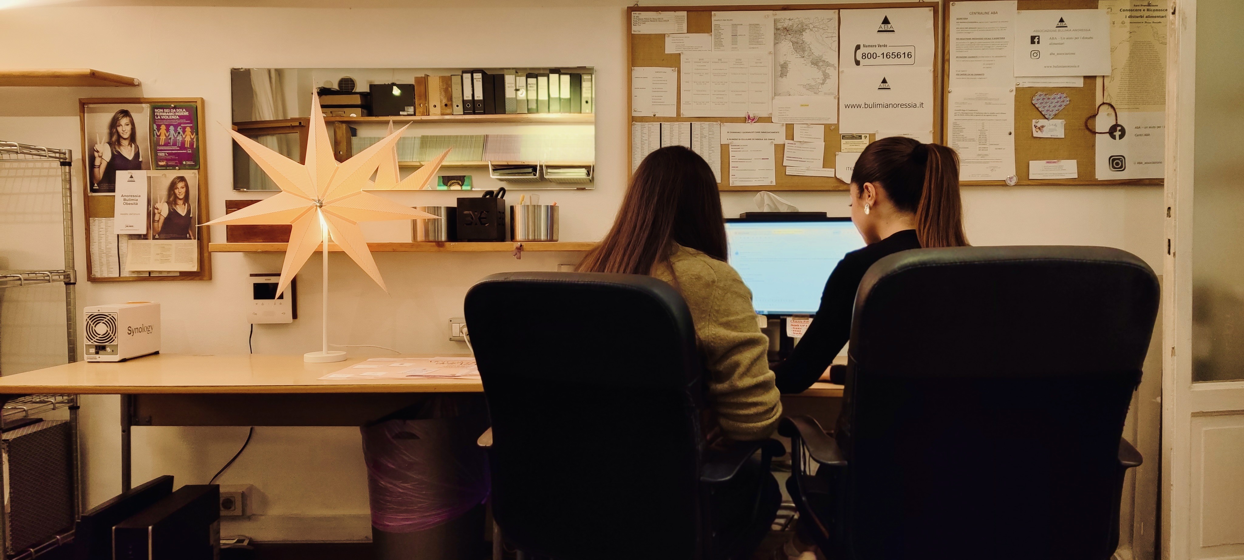 Two people working together on an electronic component, focused on a circuit board with tools visible in the foreground.