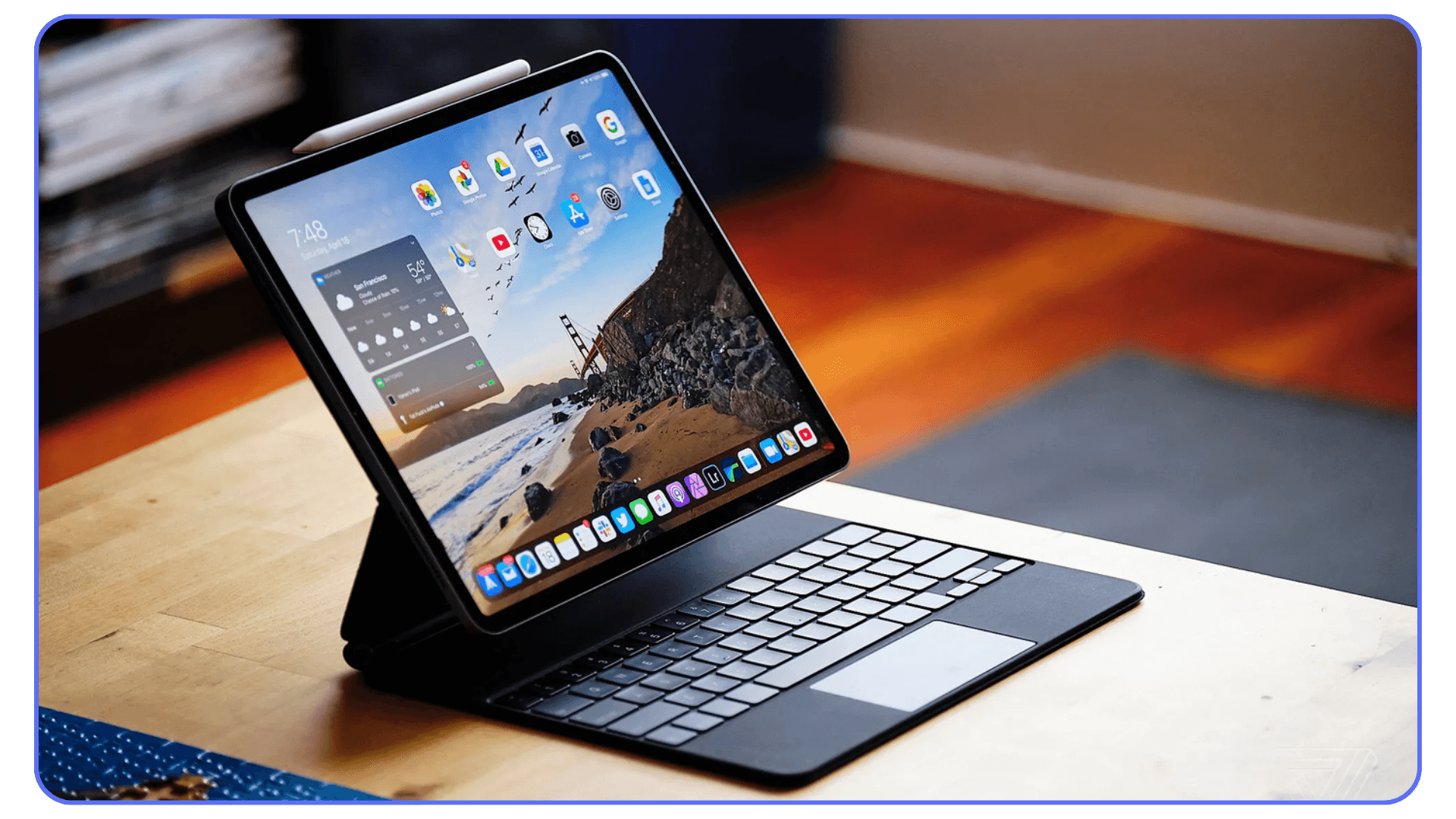 iPad connected to a Magic Keyboard on a desk, showing the home screen with widgets and dock icons.