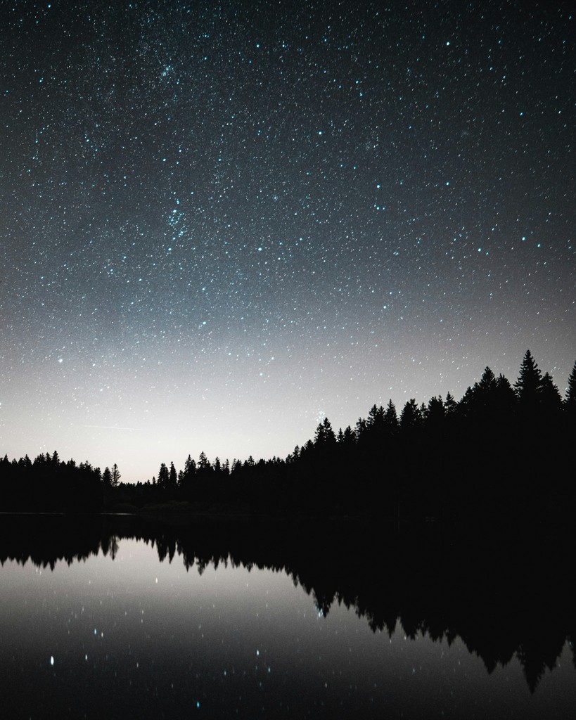Starry night sky reflected in a calm lake
