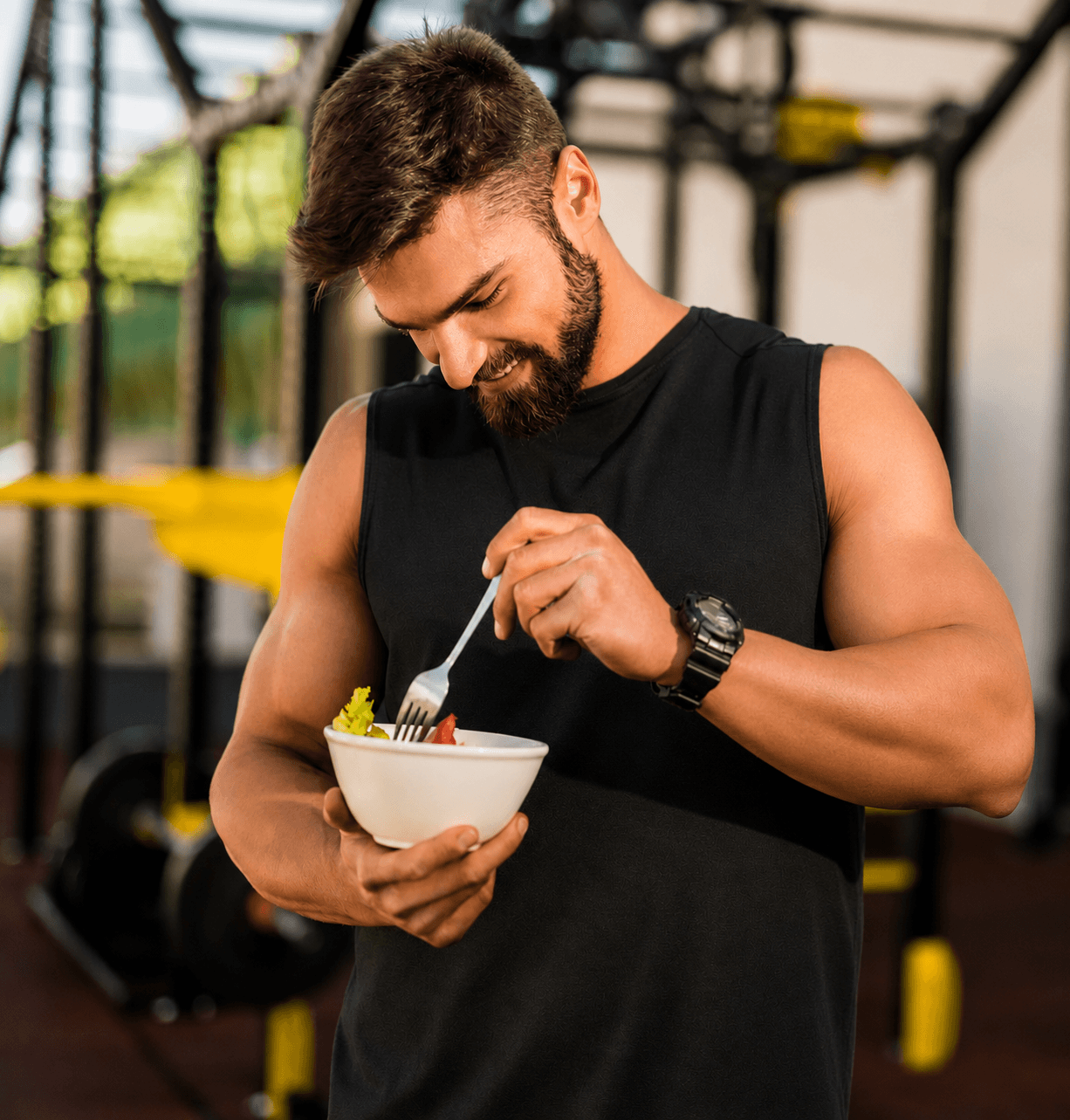 A man eating a healthy salad in a gym, highlighting the role of nutritious food in maintaining fitness.