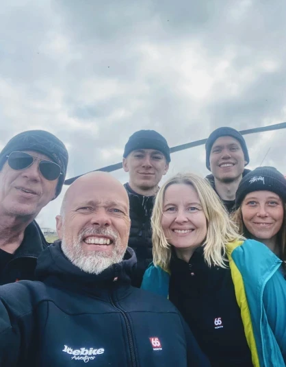 People with big smiles standing in front of a helicopter