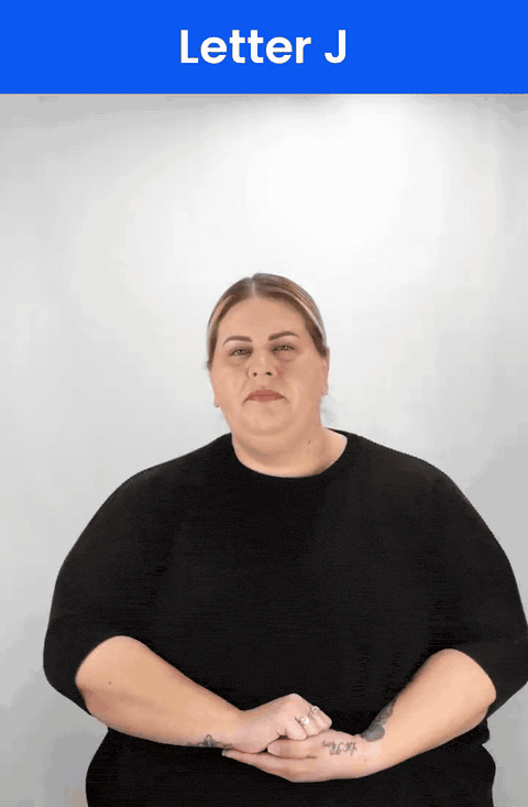 Animated GIF: a Deaf signer signs J in ASL, the little finger drawing a J as the hand twists.