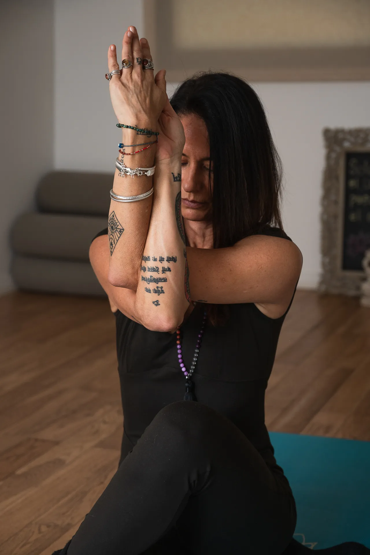 Mujer practicando una postura de yoga con los antebrazos entrelazados frente al rostro